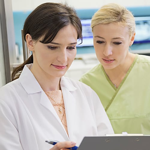  Young female technician looking into microscope in medical laboratory